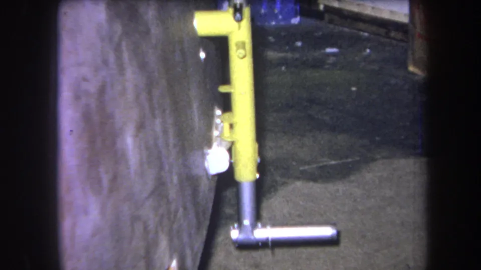 1964 Volmer Yucaipa frame with the yellow fixture centered beside rough concrete, a dark floor, and a partial blue object above.