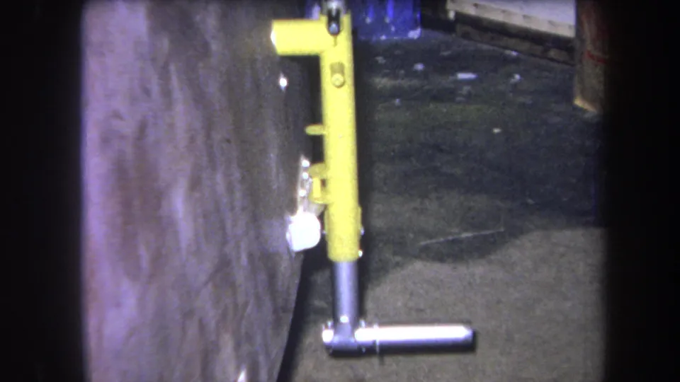 Final 1964 Volmer Yucaipa frame showing the same yellow metal fixture, silver handle, concrete wall, and dim utilitarian setting.
