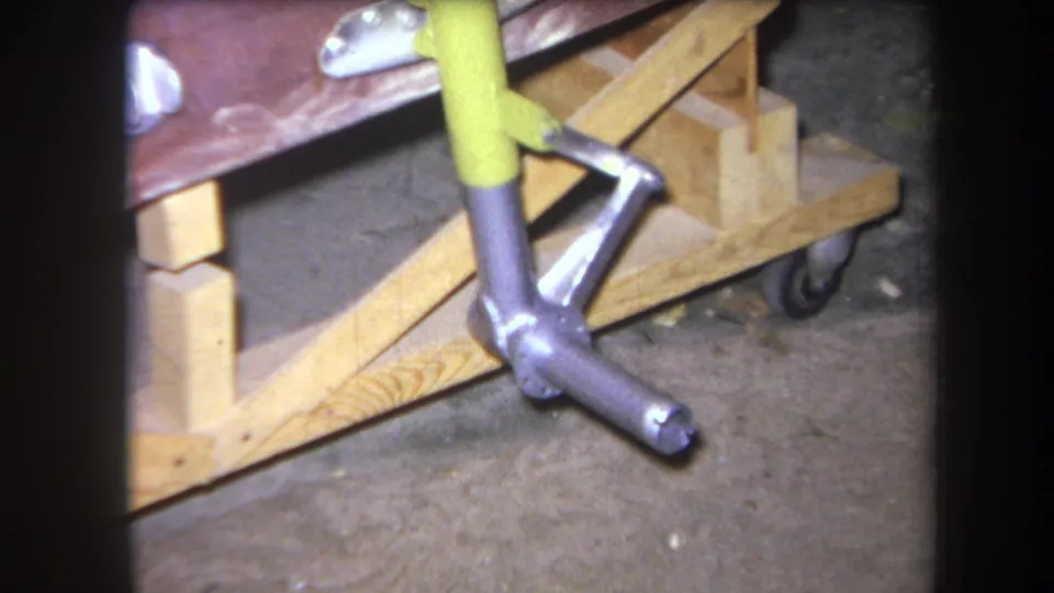 1964 Yucaipa home-movie frame showing the yellow and silver coupling beside a wooden furniture frame and small caster wheel.