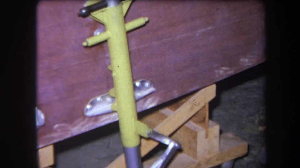 Yucaipa 1964 home-movie still showing a yellow metal tool or support beside a reddish wooden bench surface.