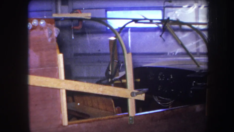 1964 Yucaipa frame showing the stripped front end of a vehicle under construction, with wood bracing and exposed tubing in a garage.