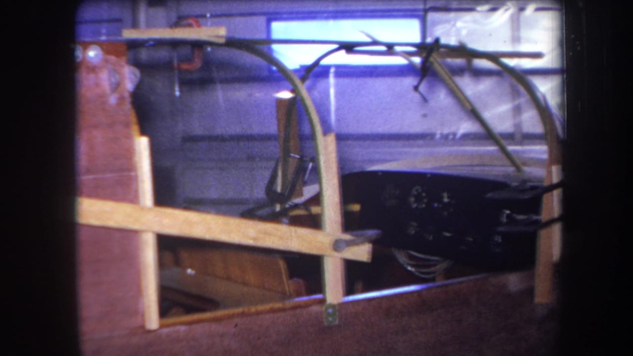 Custom vehicle cockpit under construction in a garage with wood framing and a clear curved canopy.