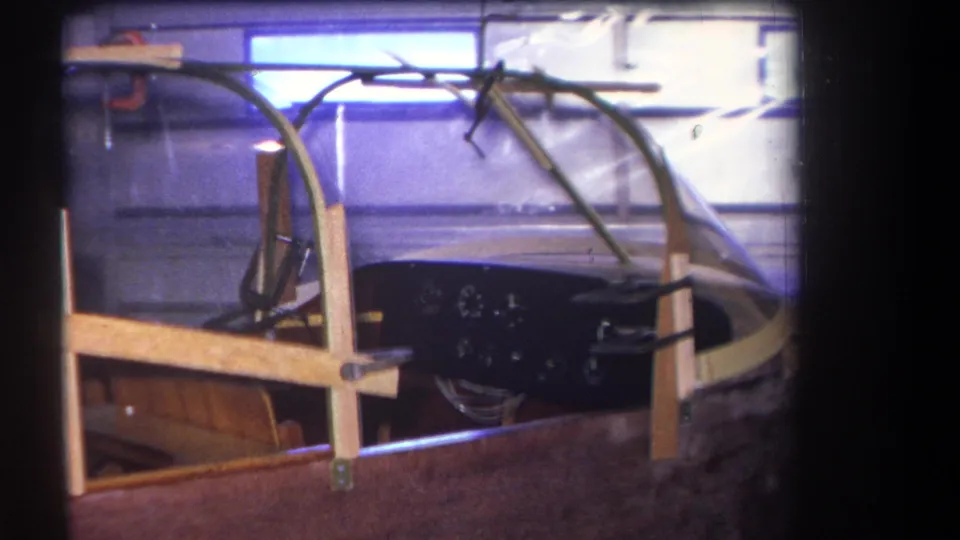 Final frame from the 1964 Yucaipa clip shows the hand-built cockpit structure with wood supports and a dark gauge panel.