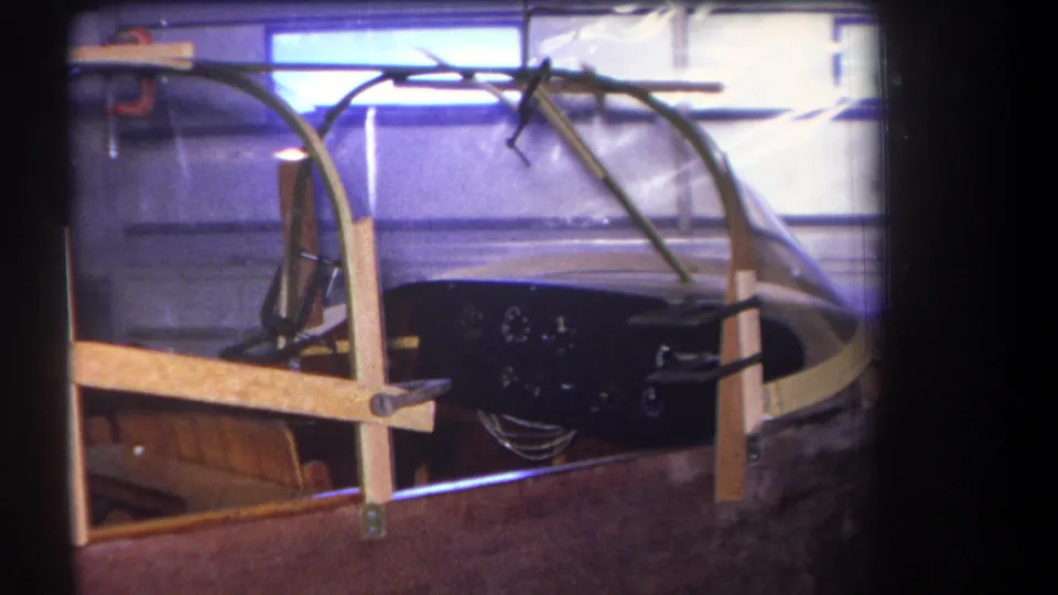 1964 Yucaipa frame of a garage-built aircraft cockpit with canopy bracing, analog instruments, and workshop windows.