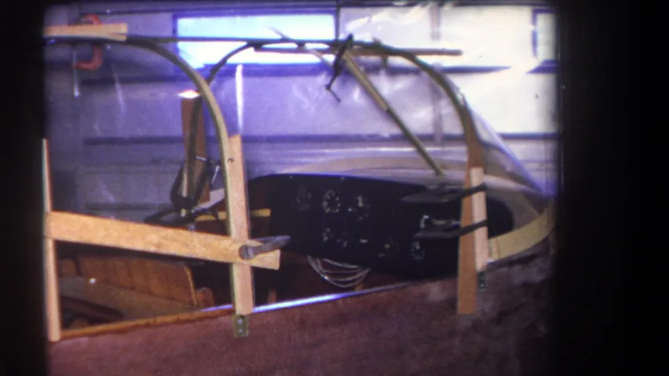 1964 Yucaipa home-movie frame of a handmade aircraft cockpit, seen close up in a garage or workshop.