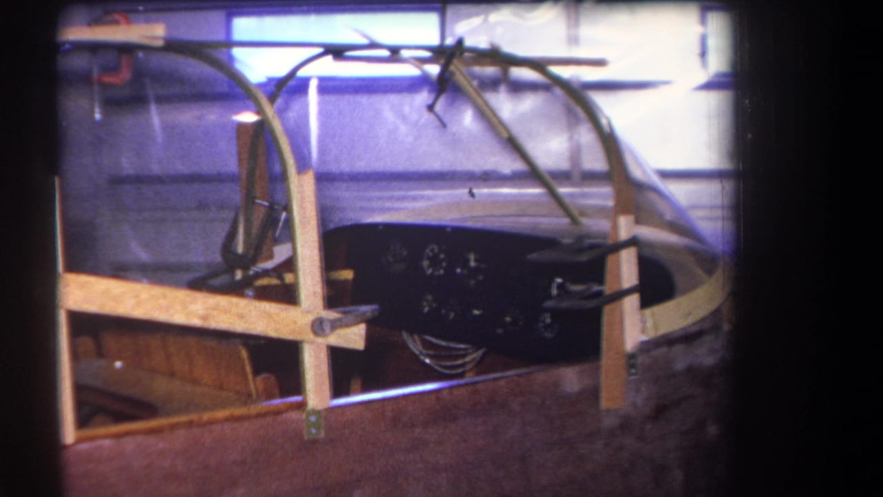 1964 Yucaipa-area 8mm frame showing a stored small aircraft cockpit with wood supports, clear canopy, gauges and exposed wiring.