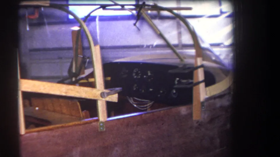 Final 1964 Yucaipa-area frame showing the quiet aircraft cockpit, clear canopy edge, wood supports and dark instrument panel.