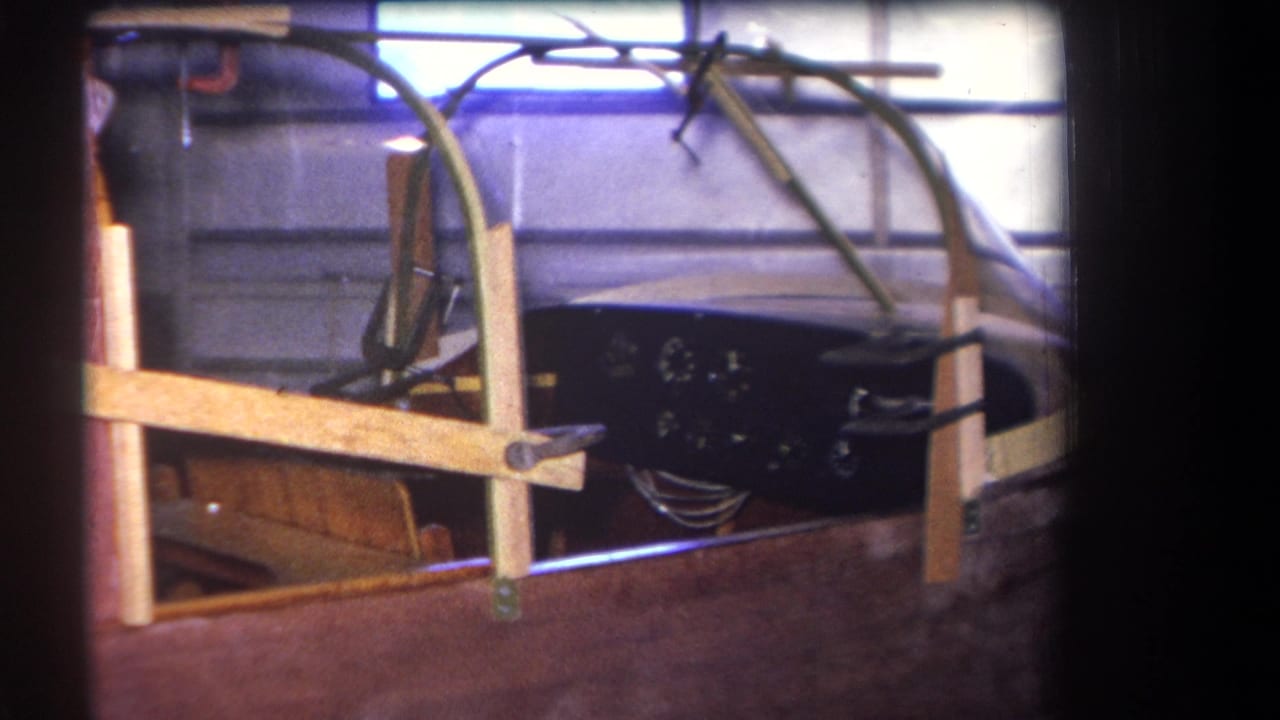 Side view of a wooden speedboat hull with canopy, gauges, and support framing.