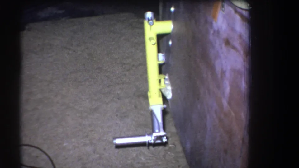 A close home-movie view of a yellow wall-mounted tool with silver hardware inside a likely workshop or garage setting.