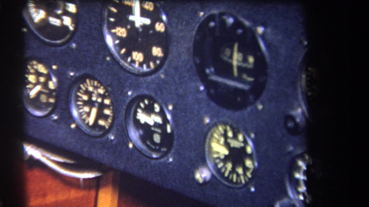 Close view of round aircraft gauges on a dark panel beside warm wood cockpit trim.