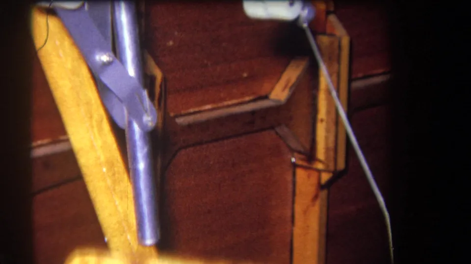 Lower close-up of the pulley assembly, with a painted metal arm, cable, and shaped wooden mounting visible.
