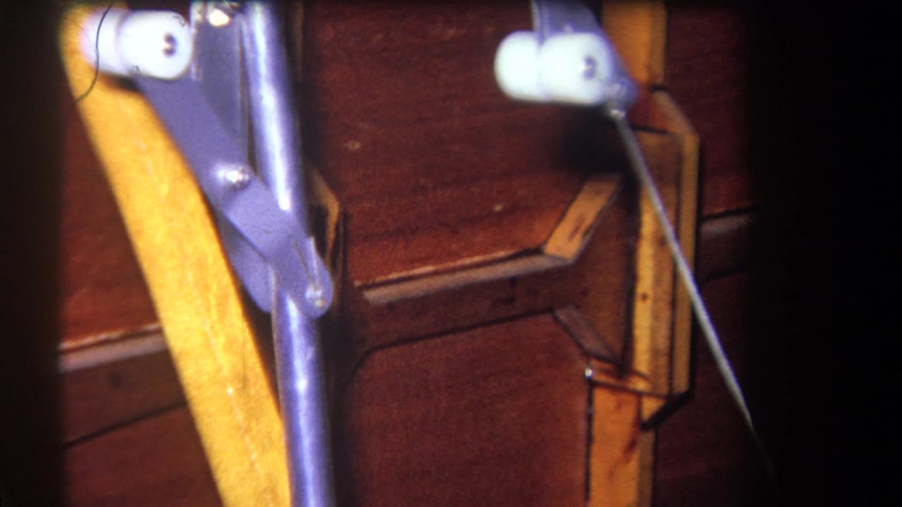 1964 8mm close-up from Yucaipa showing wooden machinery with purple metal linkage, white rollers, and thin rods.