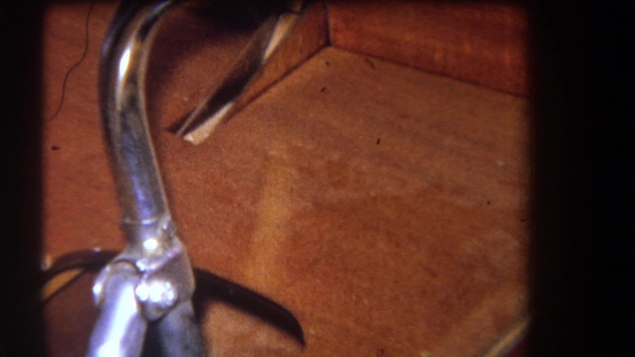 Close view of a curved metal pipe beside warm wood paneling and framing.
