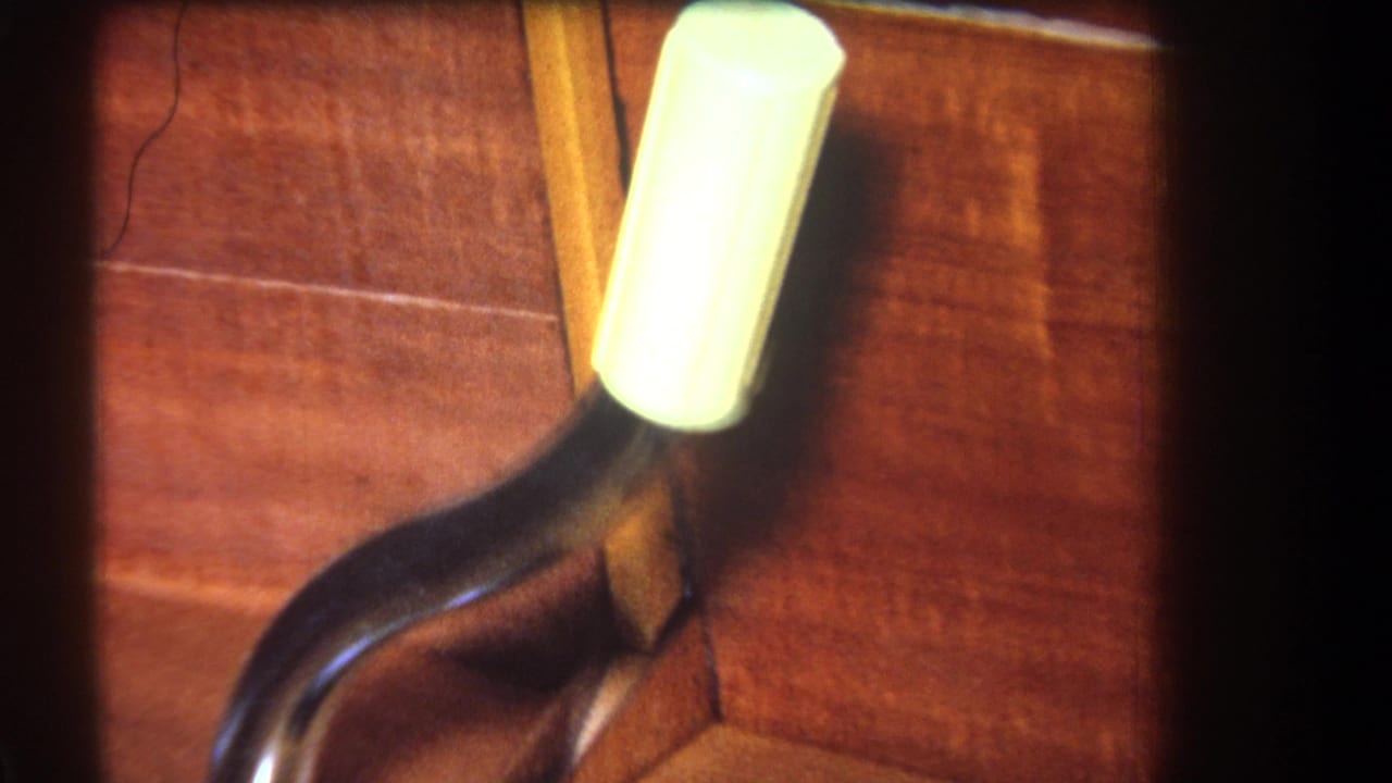 Close 1964 interior detail showing a capped metal pipe beside angled wooden framing in Yucaipa footage.