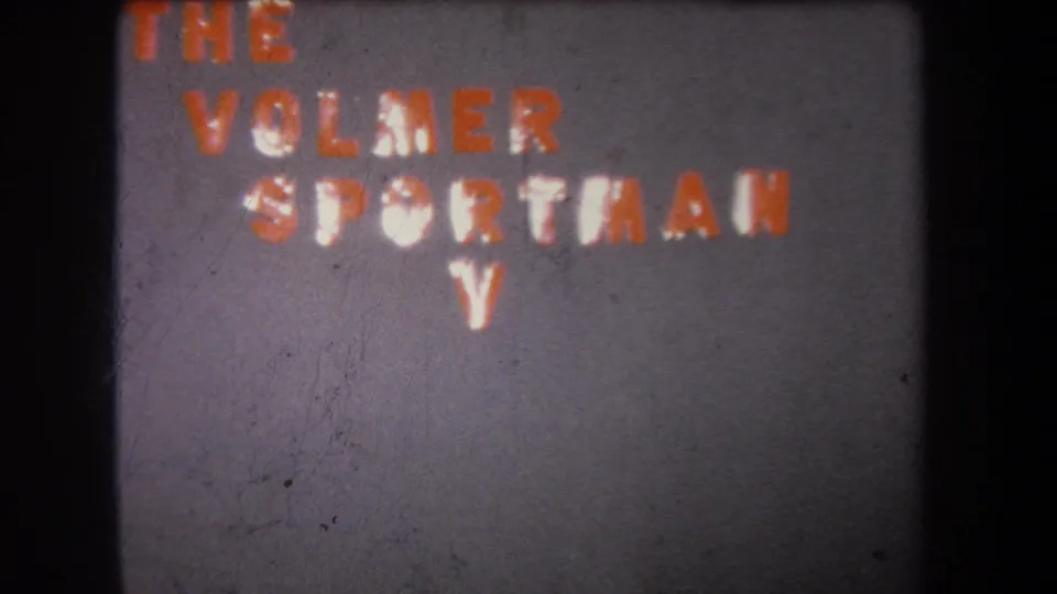 1965 8mm frame from Yucaipa, California showing handmade wall lettering for The Volmer Sportsman with a white V below.