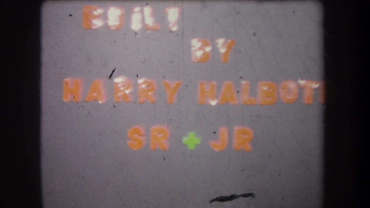 1965 8mm frame shows the Harry Halbott Sr + Jr production credit card with dust, scratches, and dark projector borders.
