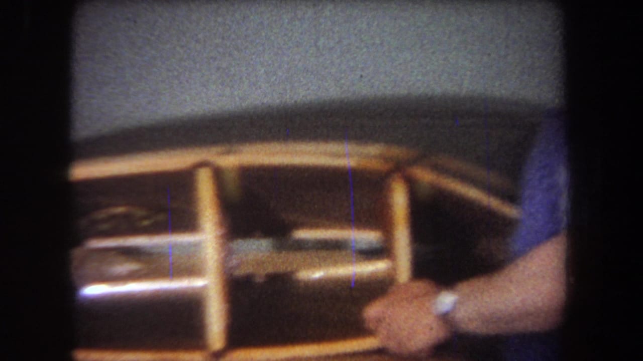 A wooden model boat is held close to the camera.