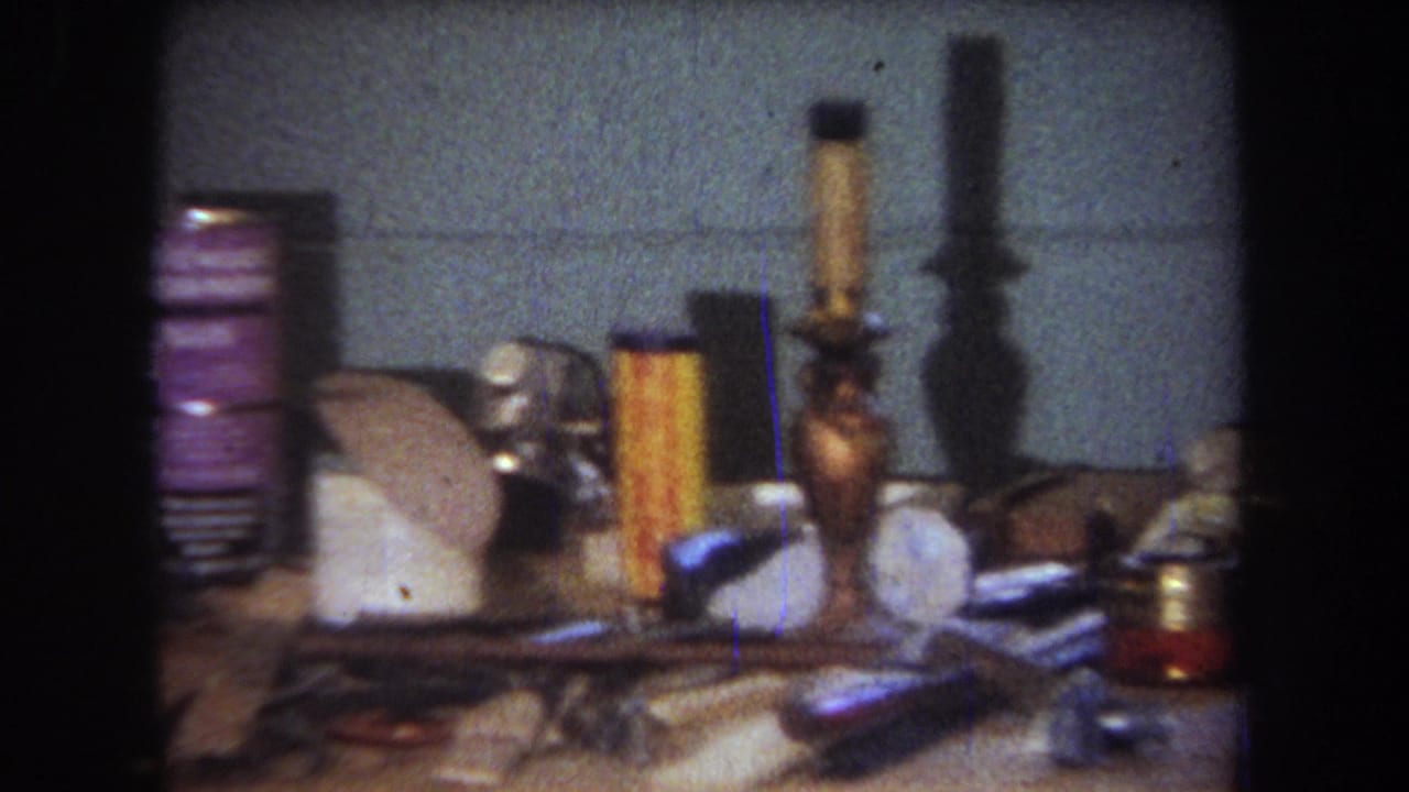 Cluttered workbench with cans, tools, cords, and craft supplies.