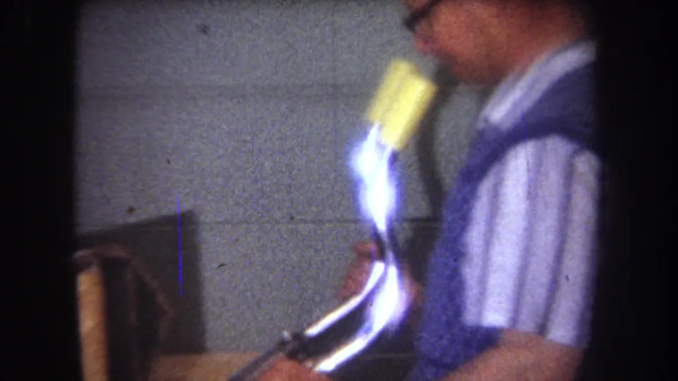 1965 8mm frame from Yucaipa showing a blurred adult man moving inside a workshop-like space before the aircraft frame shots.