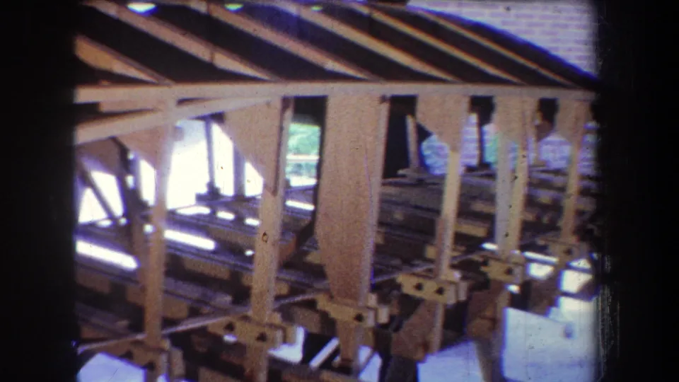A closer 1965 workshop view shows the aircraft's wooden ribs and truss members, with daylight visible through the structure.