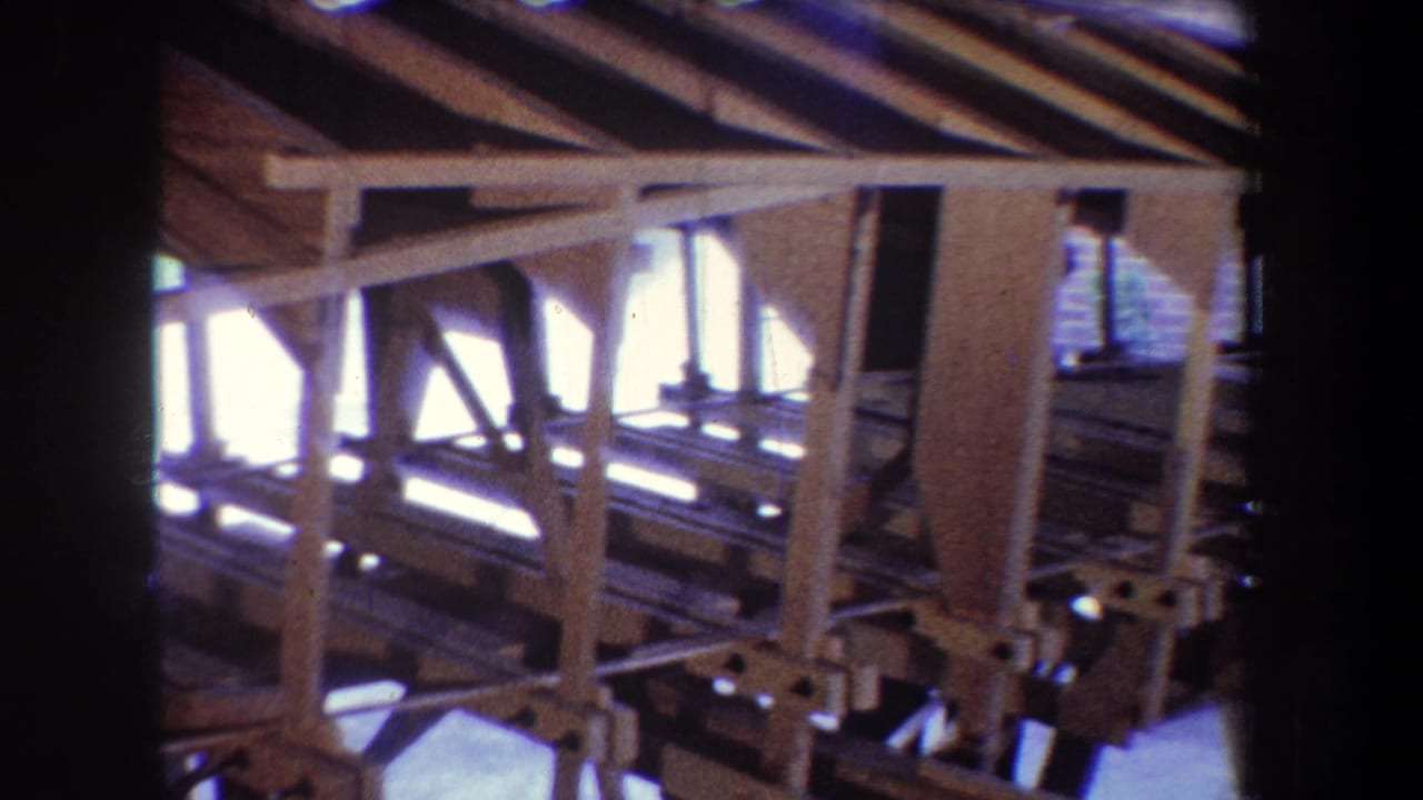 Unfinished wooden framing with beams, posts, and bright light beyond the wall openings.