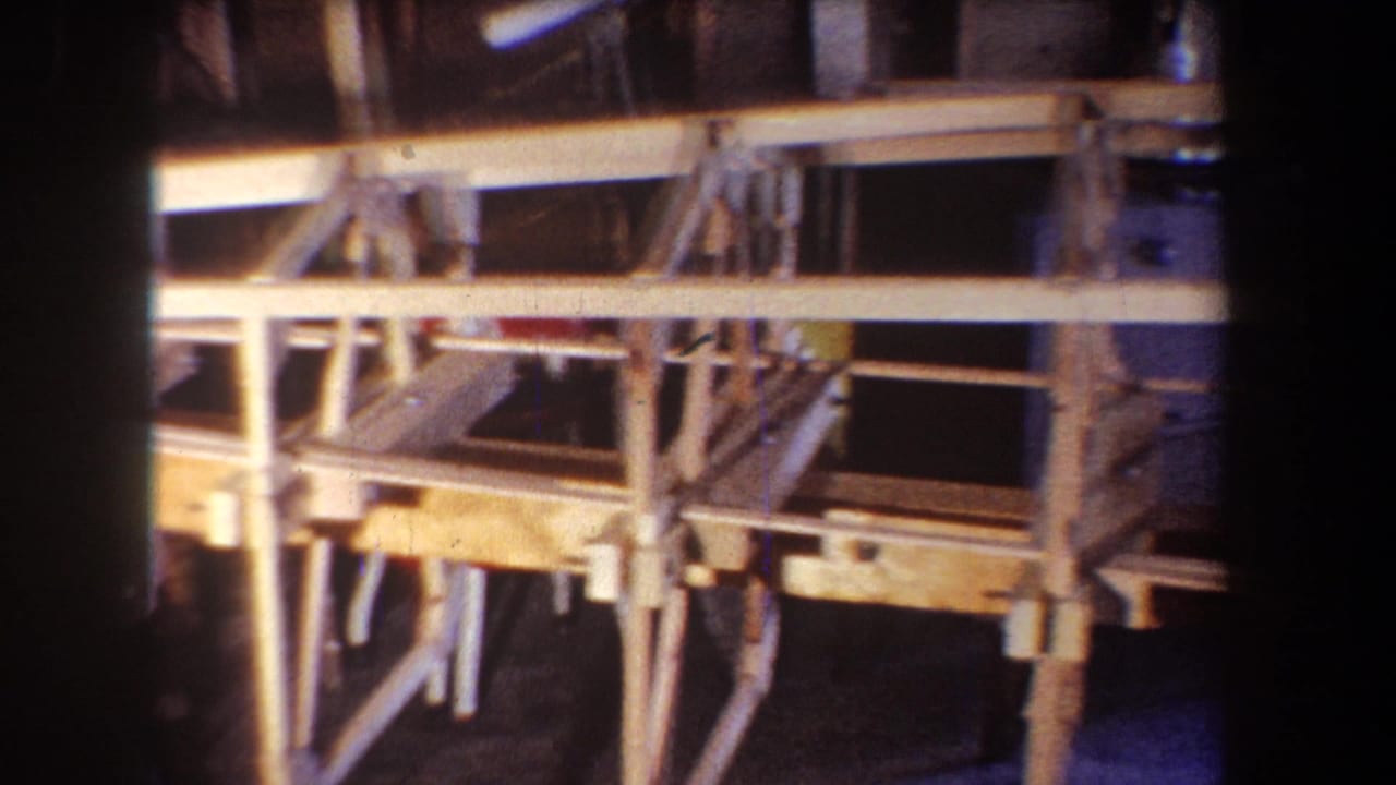 1965 Yucaipa-area 8mm frame showing light-colored wooden boat framing, cross braces, and support legs inside a workshop.