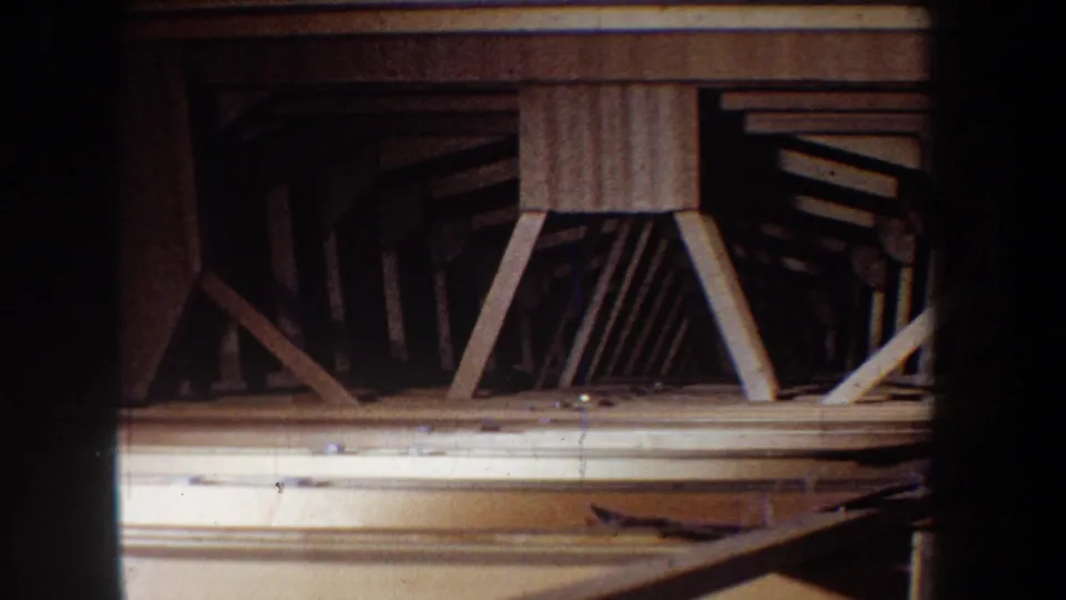 Darker 8mm frame from the 1965 Yucaipa clip showing the side of a wooden boat frame with ribs and cross bracing.