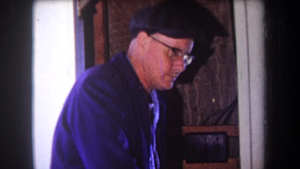 The man in a blue jacket and dark cap is seen in profile while working in the Volmer Yucaipa woodshop setting.
