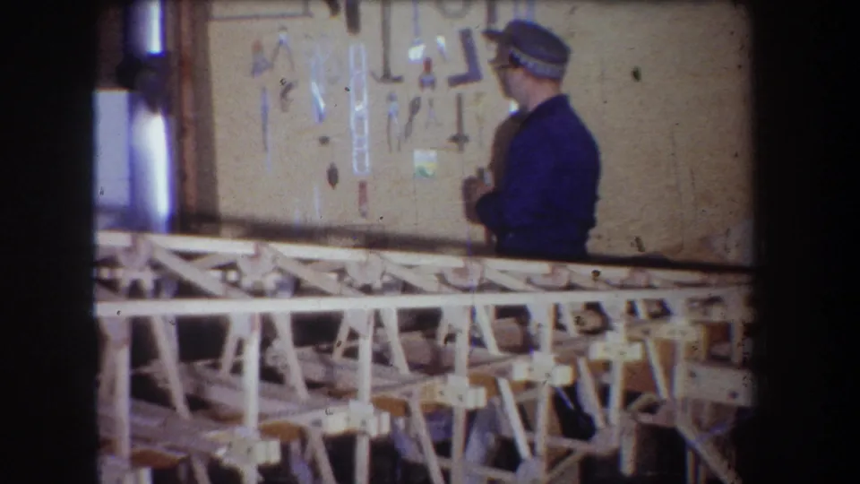 1965 Yucaipa frame showing the man beside wall-hung tools with the wooden sailplane frame spanning the lower foreground.