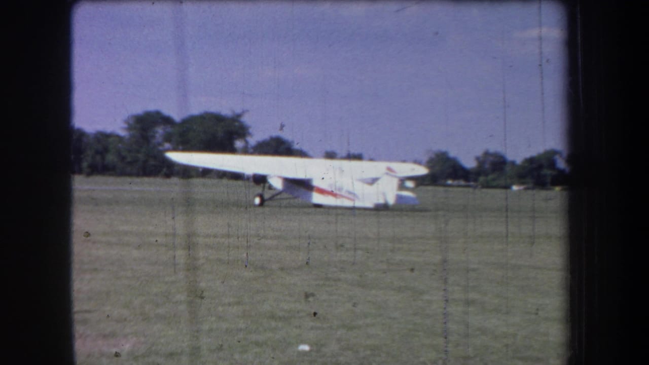 Home-movie frame from 1965 showing a white light plane on a grassy Yucaipa-area airfield.
