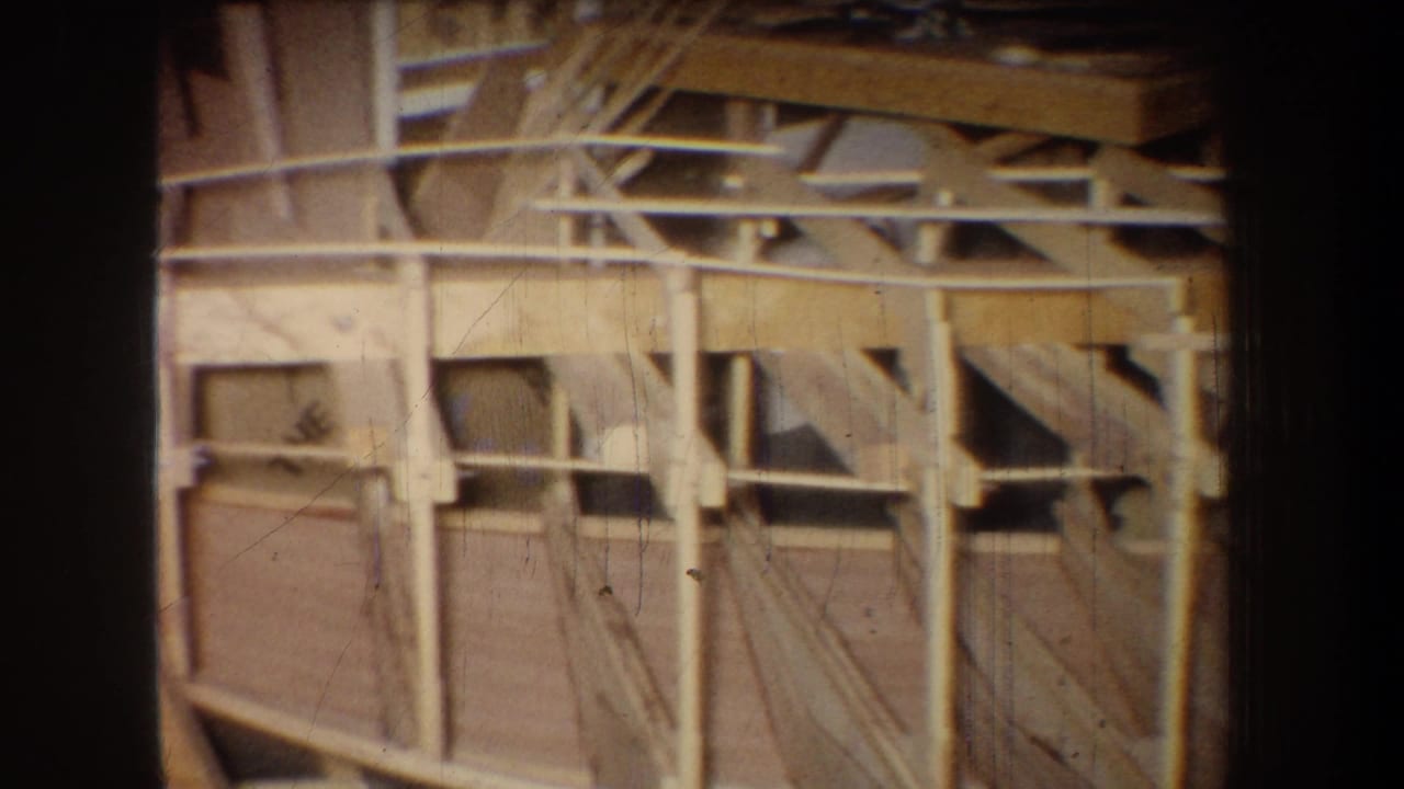 1965 Yucaipa warehouse interior showing exposed wooden beams, support posts, and diagonal bracing in warm 8mm film tones.