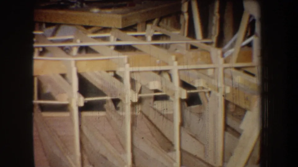 Yucaipa warehouse interior from 1965 showing repeated wooden posts, braces, and plank surfaces captured on soft 8mm footage.