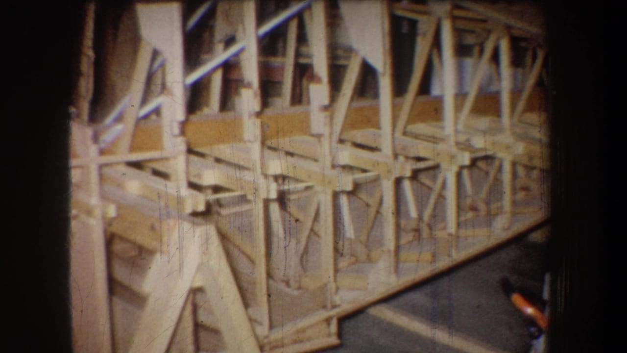 Longer section of wooden framework extending across a workshop floor.
