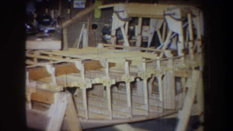 1965 Yucaipa frame showing the end of a hand-built wooden structure, including diagonal braces, rail-like members, and workshop surroundings.