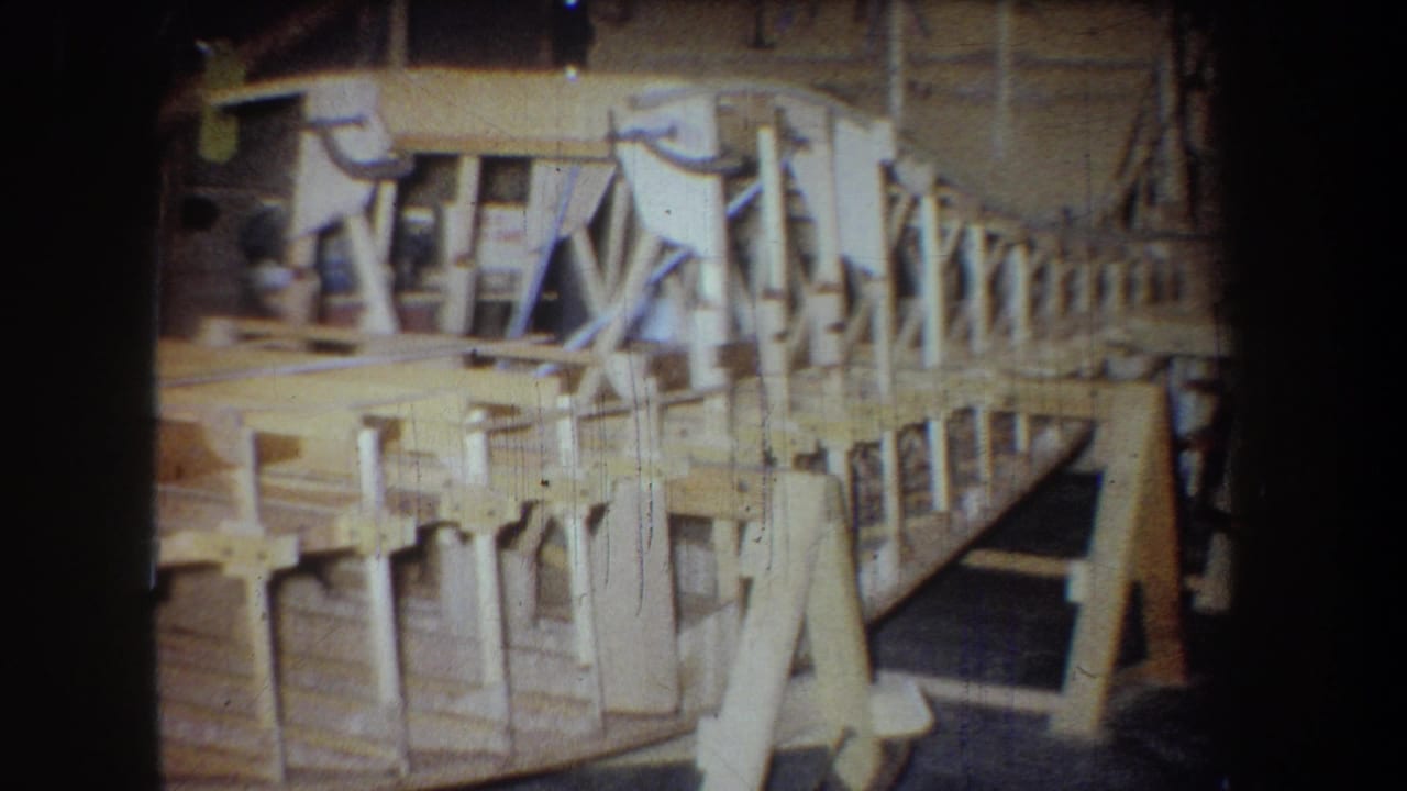 Side view of a wooden airplane skeleton with bracing and supports.