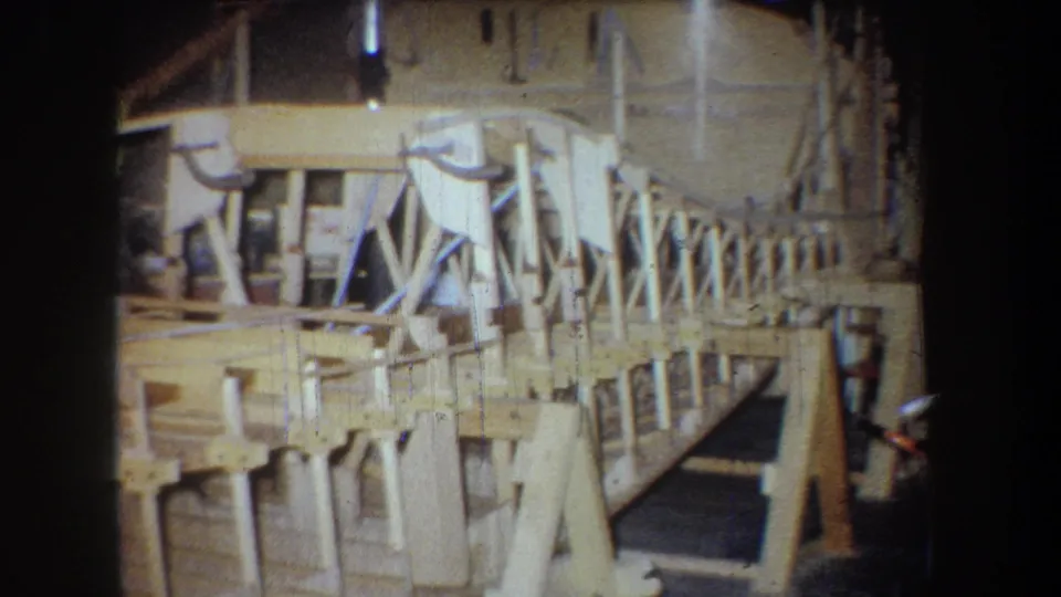 Final frame of the 1965 Yucaipa workshop view, showing the unfinished wooden aircraft frame on supports.