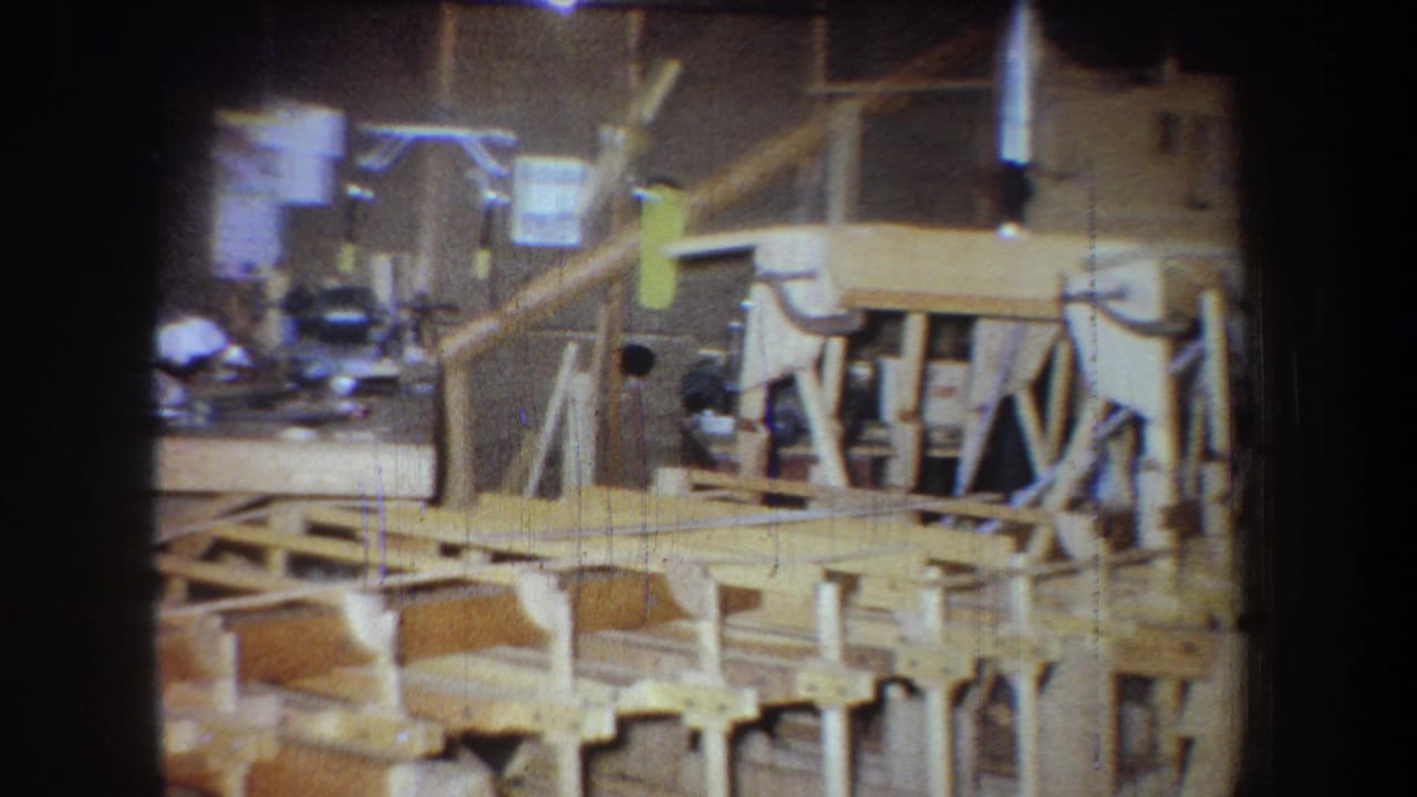 Wooden bridge frame and workshop benches seen under warm shop lighting.