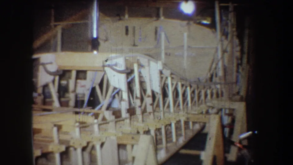 1965 Yucaipa frame showing the end section of the bridge model or small structure, surrounded by tools, lumber, and dim shop lighting.