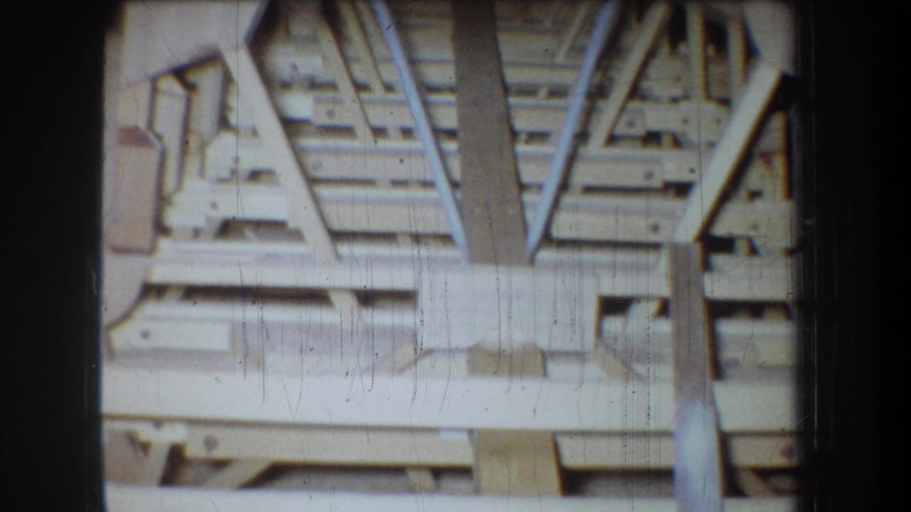 Attic ceiling framing with cross beams, vertical supports, and dark edges around the film frame.