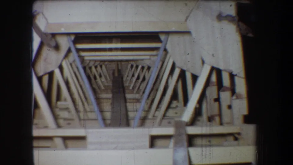 Final 1965 Volmer Yucaipa attic frame showing exposed rafters, cross boards, vertical framing, and warm home-movie texture.