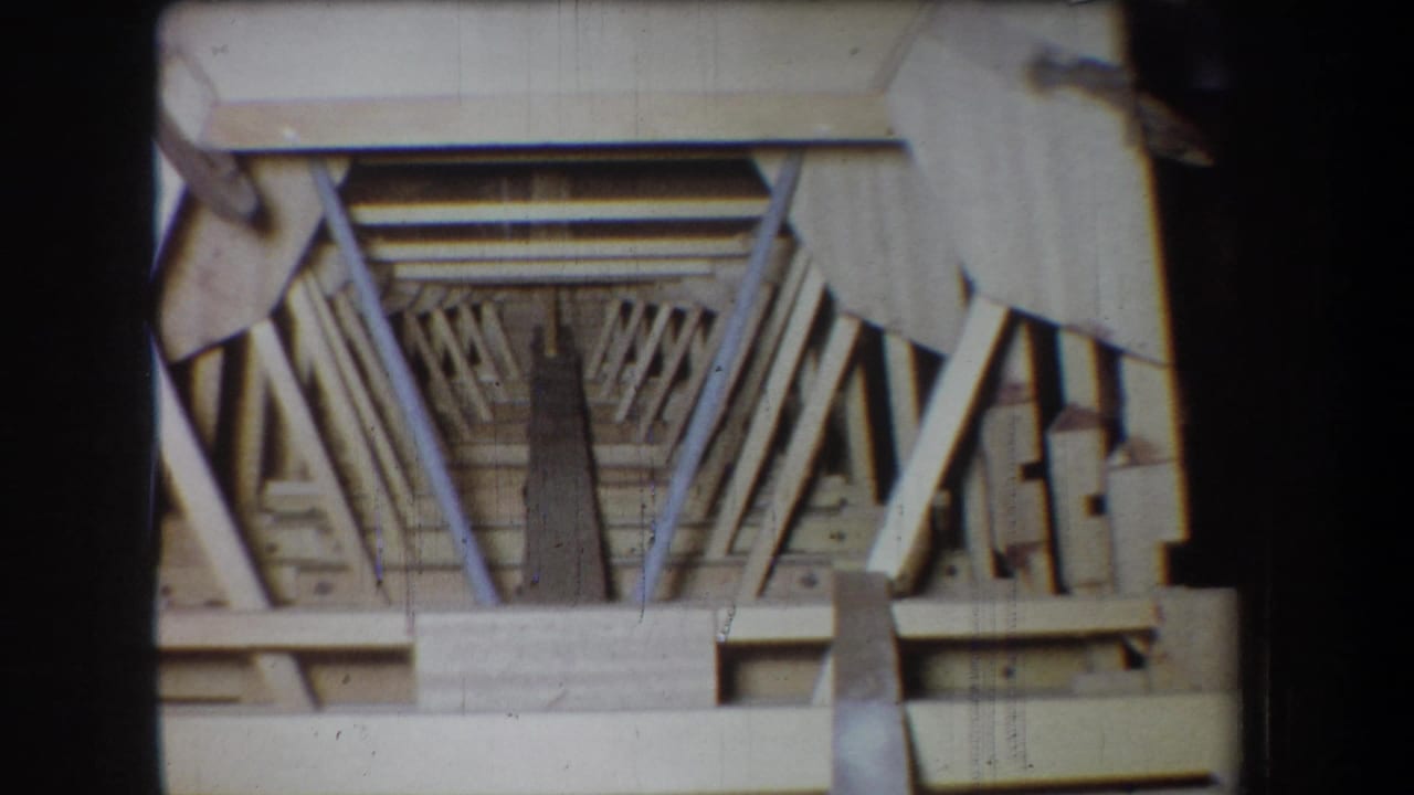 1965 Yucaipa 8mm frame showing a pale wooden structure or model with diagonal trusses and a dark central opening.