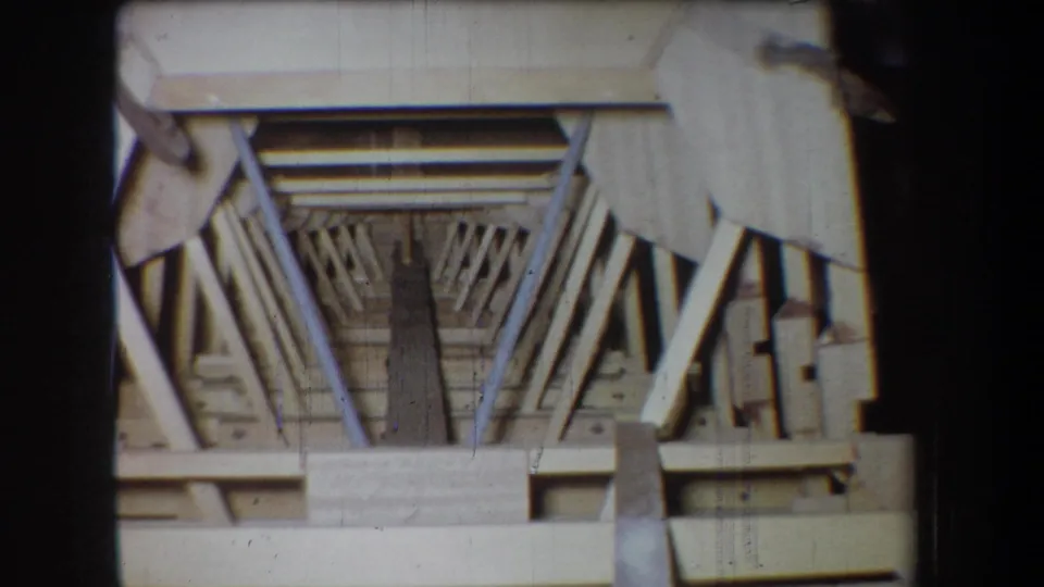 1965 Yucaipa 8mm frame showing a pale wooden structure or model with diagonal trusses and a dark central opening.