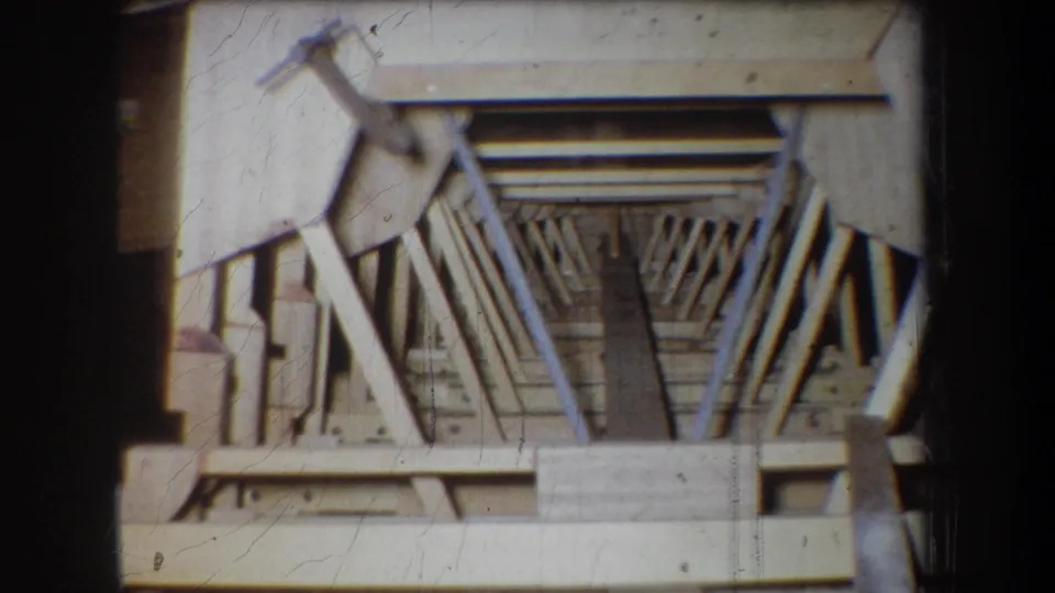 Close 8mm view of a wooden framework in Yucaipa, California, with angled braces, rails, and a narrow dark center space.