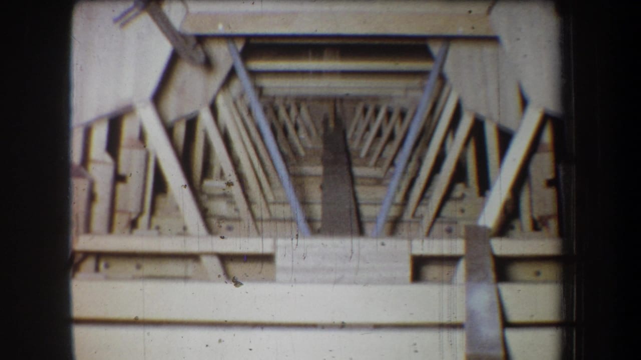 1965 home-movie frame from Yucaipa showing the front view of an unfinished small wooden aircraft structure with exposed framing.