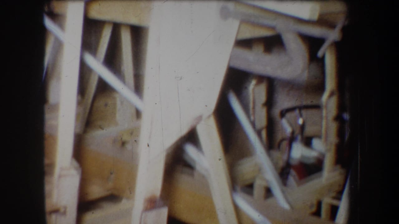 Close 1965 8mm view of a handmade wooden model structure in Yucaipa, showing beams, joints, and cross-bracing detail.