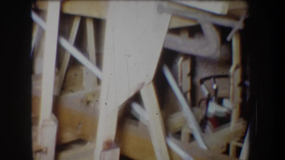 Close 1965 8mm view of a handmade wooden model structure in Yucaipa, showing beams, joints, and cross-bracing detail.