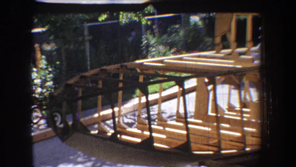 The 8mm frame shows the boat skeleton from the side, emphasizing curved ribs, deck planks, and backyard shadows.