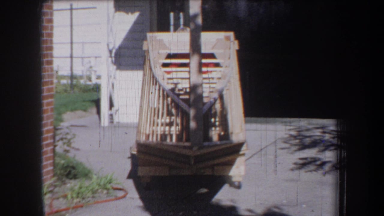 Wooden toy vehicle centered on a paved driveway in bright sunlight.