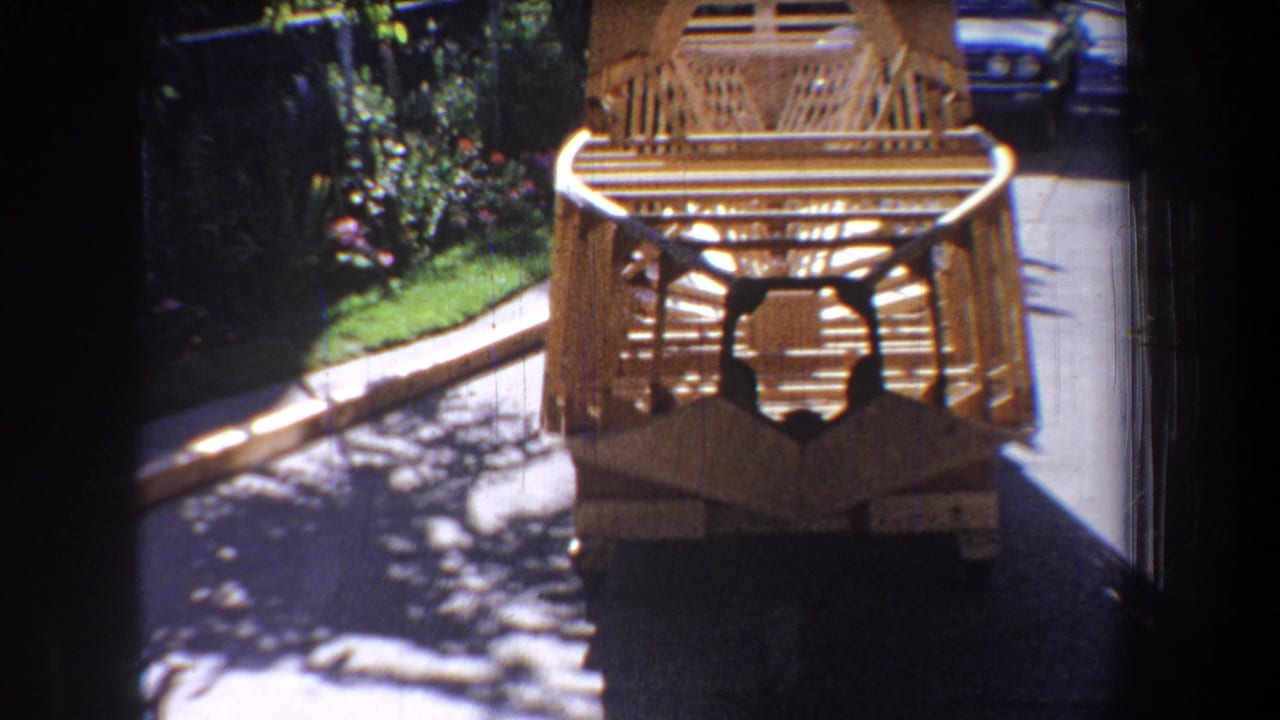 1965 Yucaipa-area home-movie frame showing a wooden aircraft fuselage structure with a circular front opening on a residential driveway.