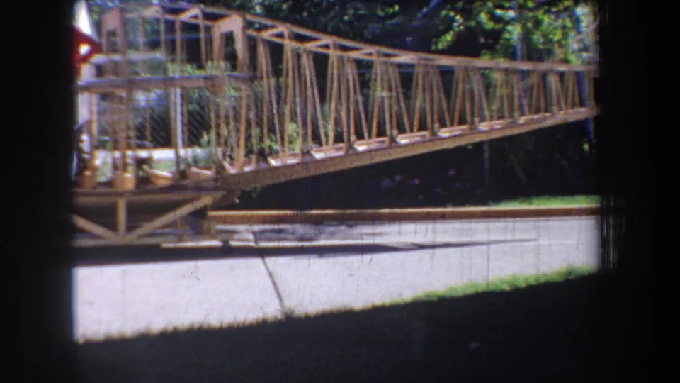 1965 Volmer, Yucaipa frame with a closer view of the bridge railing and truss work, chain-link fencing, road below, and leafy background.